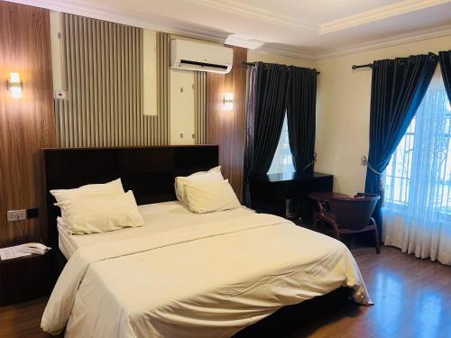 a bedroom with a large bed with white sheets at DE Lounge Inn in Ikorodu