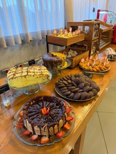 a table with many different types of cakes and pies at Transamerica Fit Contagem in Contagem