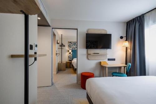 a hotel room with a bed and a desk and a tv at Sure Hotel by Best Western Nantes Saint-Herblain in Saint-Herblain