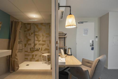 a room with a desk and a chair and a lamp at Sure Hotel by Best Western Nantes Saint-Herblain in Saint-Herblain