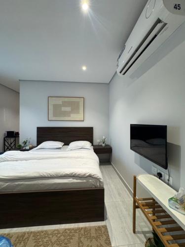 a bedroom with a large bed and a flat screen tv at Modren AD 23 in Dammam