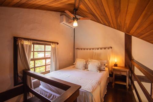 a bedroom with a bed with a ceiling fan and a window at Pousada Villaggio Assis in Ilhabela