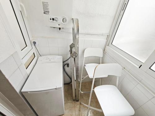 a small bathroom with white chairs and a window at Sea&Kids in Malgrat de Mar