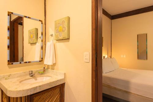 a bathroom with a sink and a mirror and a bed at Pousada Villaggio Assis in Ilhabela