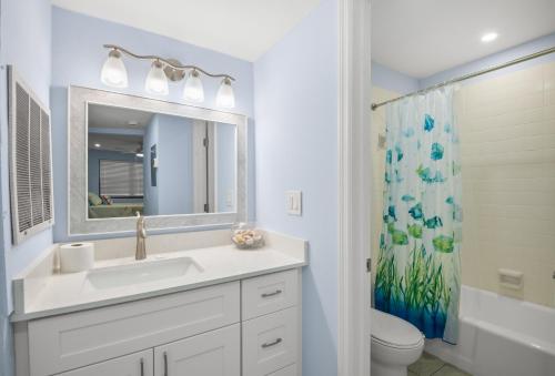 a bathroom with a sink and a toilet and a mirror at Gulf Winds Resort by Travel Resort Services in St. Pete Beach