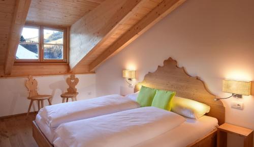 una camera da letto con un letto con lenzuola bianche e cuscini verdi di Residence Simml & Schlosser a San Candido