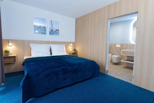 a bedroom with a large bed and a bathroom at Marina Apartamenty ChKŻ in Charzykowy