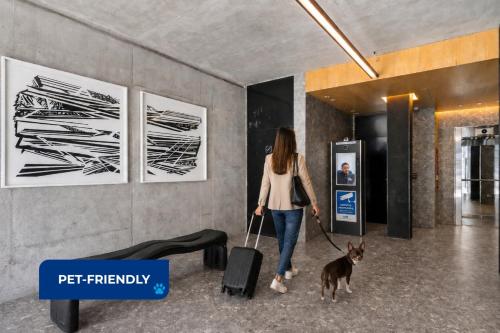 a woman walking a dog with a suitcase at Live Belgrano Boutique Apartments in Buenos Aires