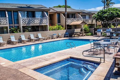 a swimming pool with chairs and a table next to a building at 214 Kihei Holiday in Kihei