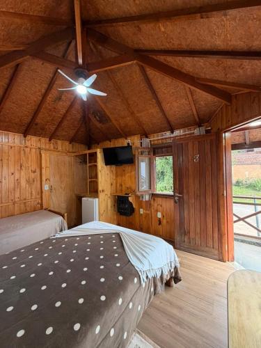 a bedroom with a bed and a ceiling fan at Chales Vale da Nascente in Monte Verde