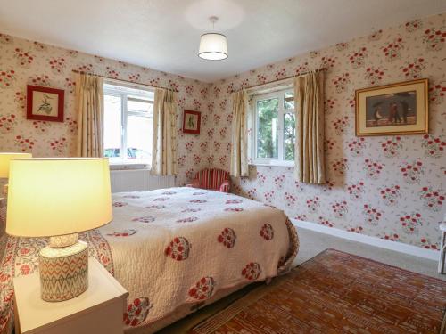 a bedroom with a bed with floral wallpaper at The Lodge in Colchester