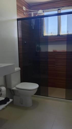 a bathroom with a toilet and a glass shower at Refúgio da praia in Serra