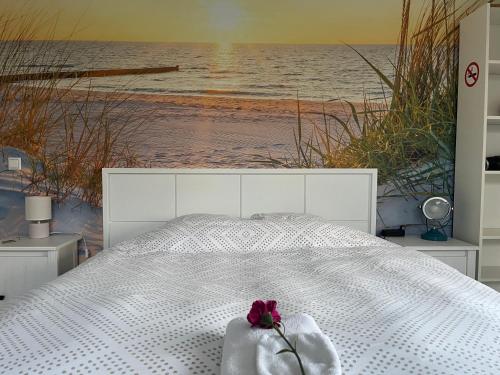 a white bed with a pink flower on top of it at De Groene Oase in Harkstede