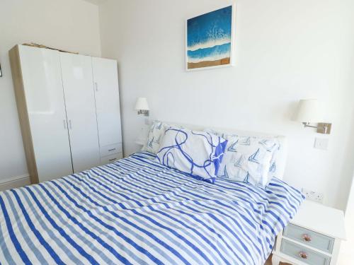 a bedroom with a bed with blue and white stripes at Ewyn Y Don in Holyhead