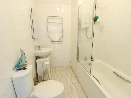 a white bathroom with a toilet and a sink at Ewyn Y Don in Holyhead