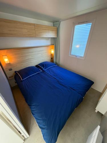 a large blue bed in a room with a window at Chalet Masion Meerwijck 6 aan het Zuidlaardermeer in Kropswolde