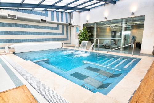 ein Schwimmbad mit Springbrunnen in einem Gebäude in der Unterkunft ARVA Spa París in León
