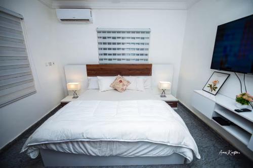 a bedroom with a white bed and a flat screen tv at Eljay Luxury Stay in Ashalebotwe