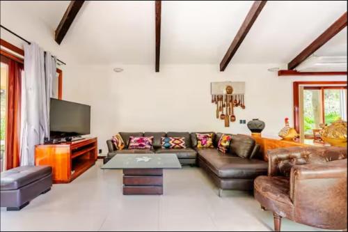 a living room with a couch and a tv at Villa con piscina y acceso a laguna Yalku, Akumal in Akumal
