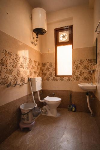 a bathroom with a toilet and a sink and a window at LVMR DORMS MOHAL Bhuntar in Shamshi