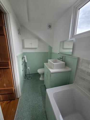 a bathroom with a tub and a sink and a toilet at The Old Milking Parlour at Knapp Farm in Dorchester