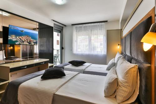 two beds in a hotel room with a flat screen tv at Villa Dvor Kornic in Budva