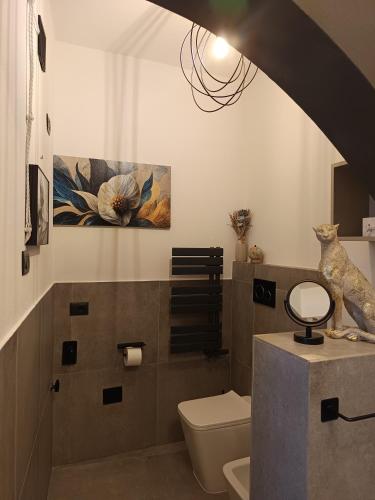 a bathroom with a toilet and a painting on the wall at Domos Le Due Tuie in Piscinas