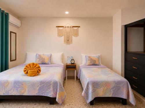 a bedroom with two beds and a cross on the wall at Cocoa by Casa Momo Apartamento Acogedor y Céntrico in Bacalar