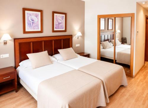 a hotel room with two beds and a mirror at ARVA Santiago León in León