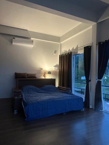 a bedroom with a blue bed and a window at Boonfarm&homestay in Ban Nop Hak