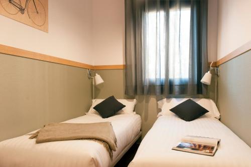 2 Betten in einem kleinen Zimmer mit Fenster in der Unterkunft MH Apartments Gracia in Barcelona