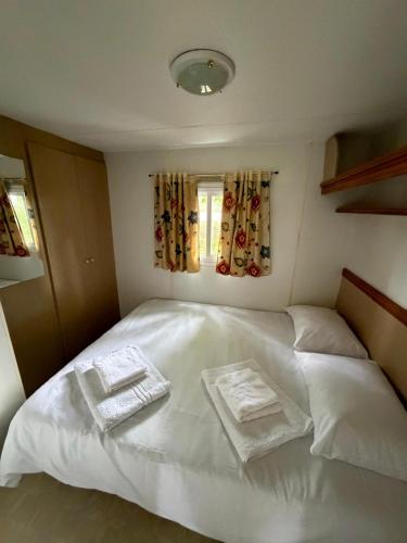 a bedroom with a white bed with two towels on it at Sid's mobile home - Camping Riba Roja in Riba-roja d'Ebre