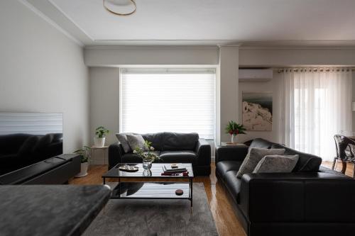 a living room with a black couch and a table at Oly modern apartment in Katerini