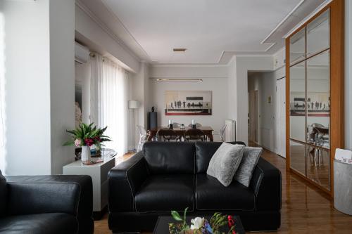 a living room with a black leather couch and a table at Oly modern apartment in Katerini
