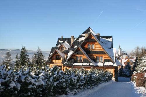 a house with a snow covered porch and trees at Holiday Home Krzysztoforow in Zakopane