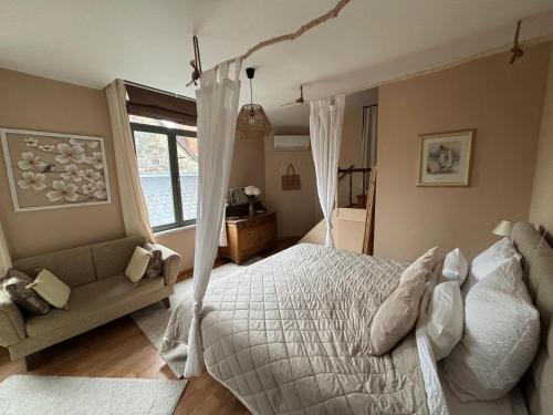 a bedroom with a white bed and a couch at Au petit nid Froissart in Chimay