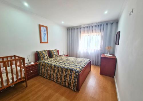 a bedroom with a bed and a window and a crib at Casa do Telhal in Vila Nova de Gaia