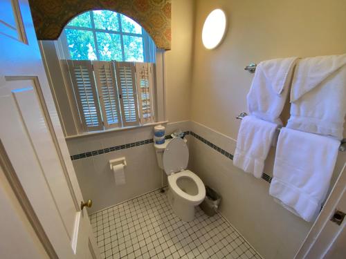 a bathroom with a toilet and a window and towels at Beaumont Inn in Harrodsburg