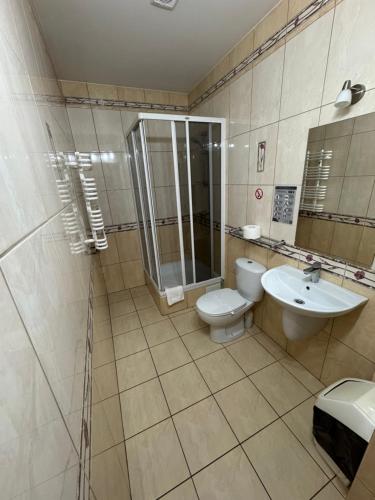 a bathroom with a toilet and a shower and a sink at Motel Okoń in Orzysz