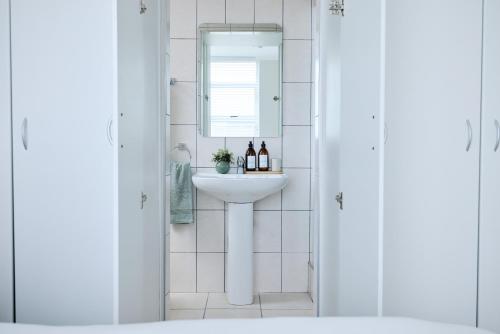 a bathroom with a sink and a mirror at 2 Bedroom Bloubergstrand Apartment with Ocean Views in Bloubergstrand