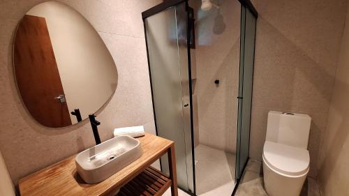 a bathroom with a sink and a toilet and a mirror at Vila no Rosa Hospedaria in Praia do Rosa