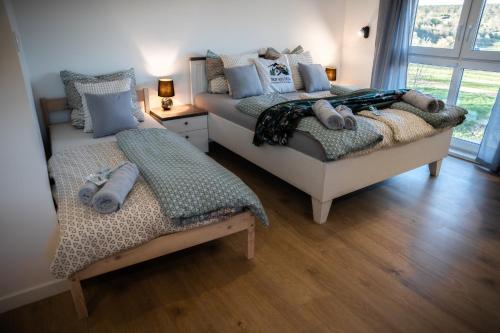 two beds in a room with wooden floors at Trzy Wzgórza Huwniki in Huwniki