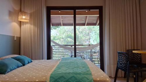 a bedroom with a bed and a large window at Vila no Rosa Hospedaria in Praia do Rosa