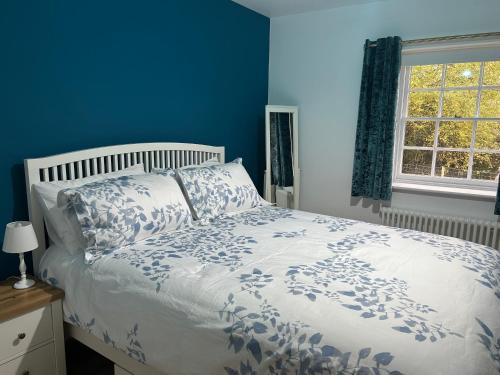 a bedroom with a bed with blue walls and a window at Country Cottage with moat in Ingatestone