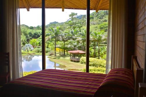 a bedroom with a bed and a large window at Macaw Lodge in Carara