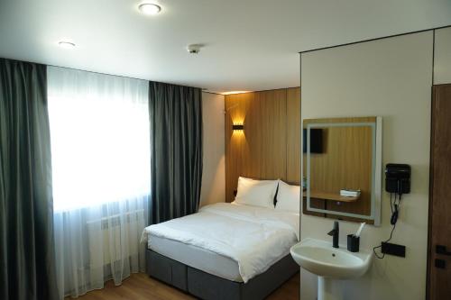 a bedroom with a bed and a sink and a mirror at Alsun Hotel in Astana