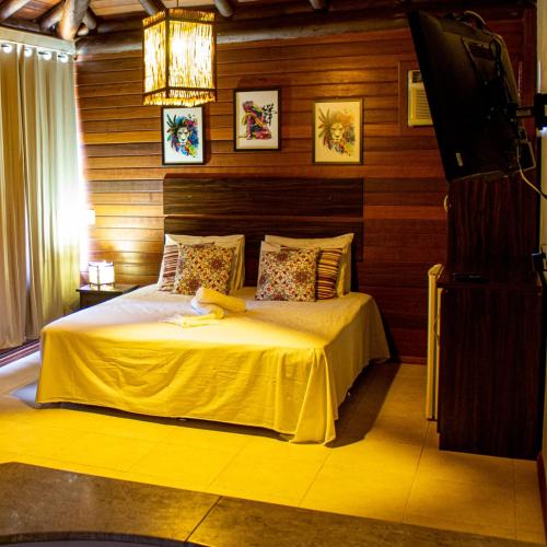 a bedroom with a bed and a chandelier at Pousada Halliny do Rosa in Praia do Rosa