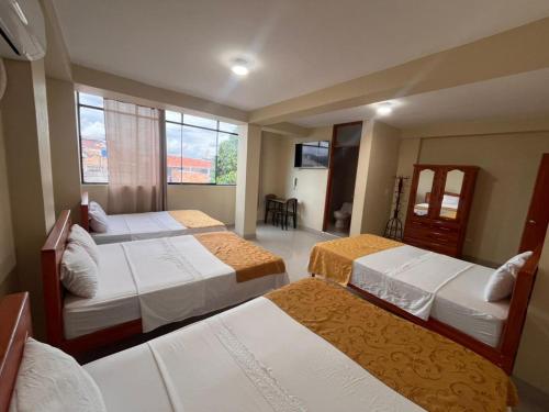 a hotel room with three beds and a window at California Bambú in Iquitos