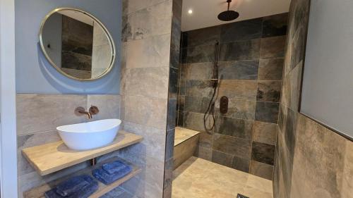a bathroom with a sink and a shower with a mirror at Country Cottage with moat in Ingatestone