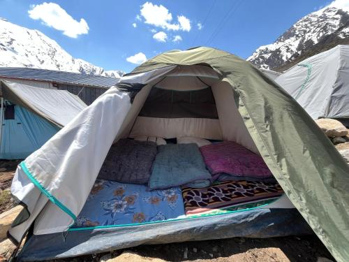 a bed in a tent with mountains in the background at The Kedar Stay in Kedārnāth